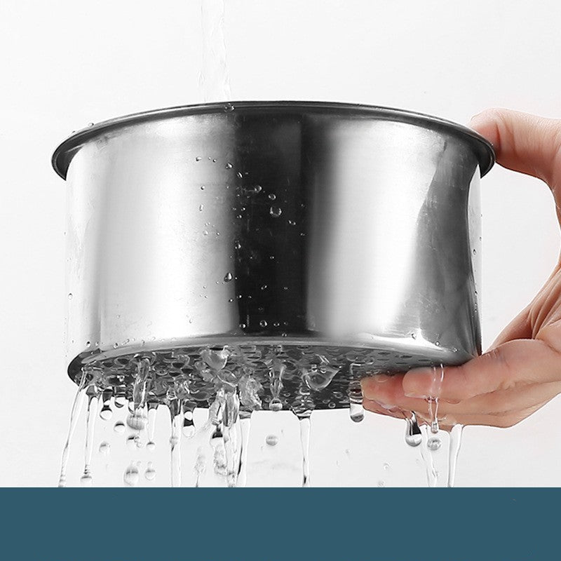 Stainless steel pot with water being poured over it, held by a hand.