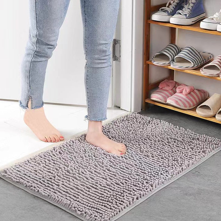 Person stepping onto a gray Super Absorbent Door Mat with shoes and slippers on a shelf in the background.