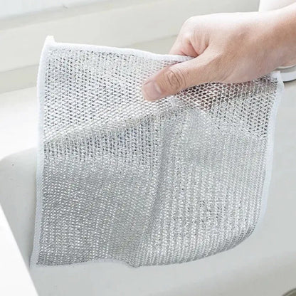 Hand holding a silver mesh scrubber over a white surface