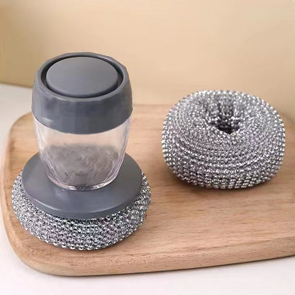 Soap dispenser with gray lid and base, and metallic scrubber on a wooden board.